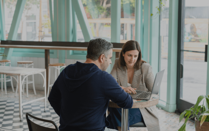 Two people talking about business with a computer