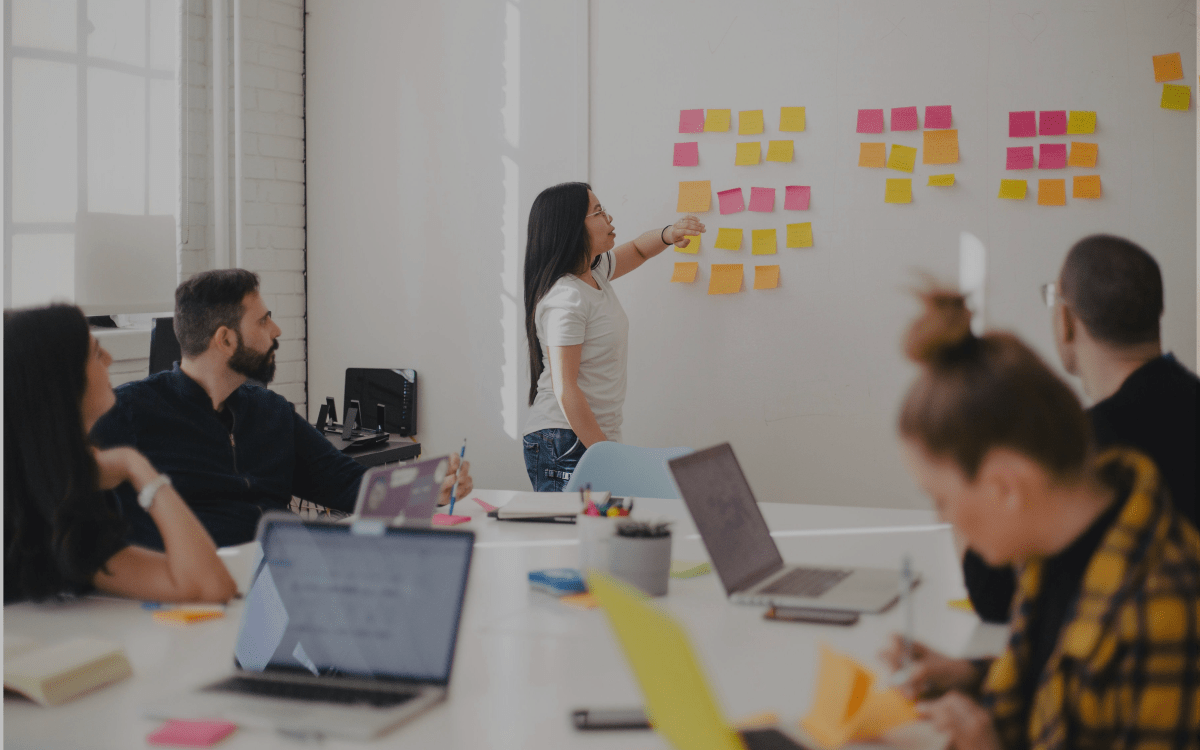 People working in a conference room with sticky notes on a whiteboard