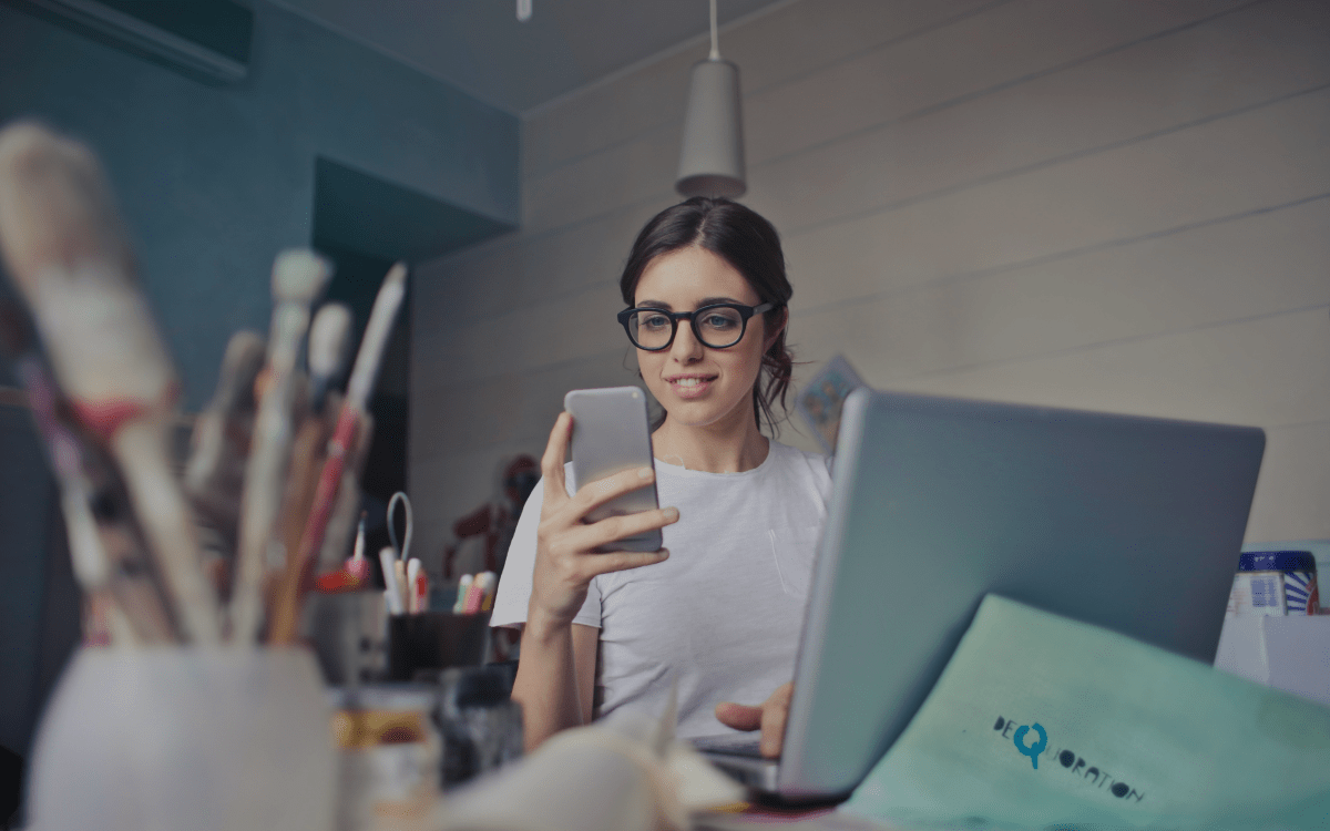 Girl on a computer looking at her phone